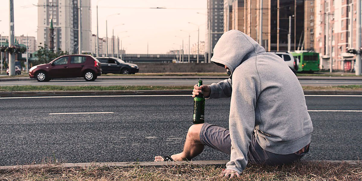 Un joven bebe una cerveza en la carretera