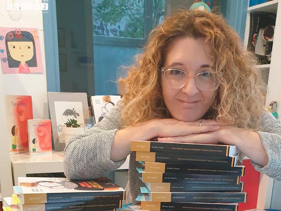 Leticia Garcés Larrea apoyada sobre una pila de ejemplares de su segundo libro 'Infancia bien tratada, adolescencia bien encaminada'