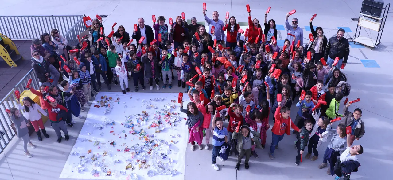 Los participantes en la iniciativa rodean los envoltorios de los almuerzos y saludan con los nuevos porta bocadillos