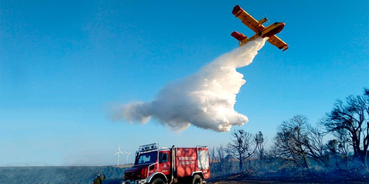 Un avión Foca realiza una descarga de agua sobre los árboles afectados por el incendio