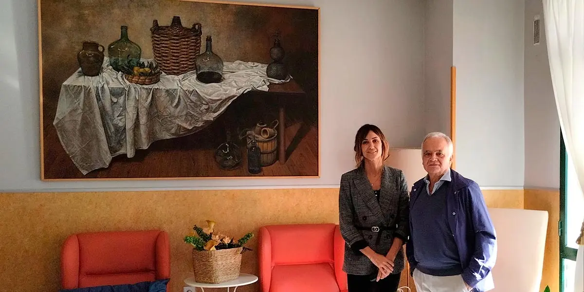 La directora de la residencia Bego&ntilde;a Moreno Valencia y el pintor Jan D&iacute;ez posan ante el cuadro donado