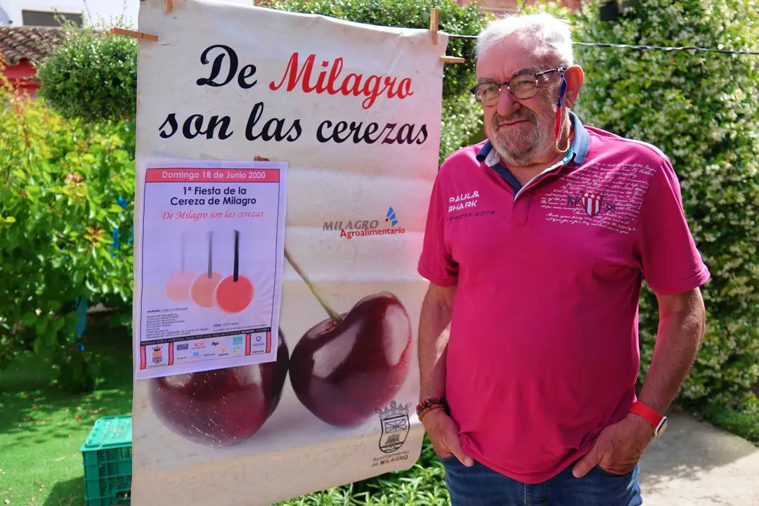 Jesus Mari Barrado Pardo posa al lado de un cartel anunciador de la Fiesta de la Cereza sobre el que está también el que lució  la I Fiesta de la misma, all&aacute; por el año 2000