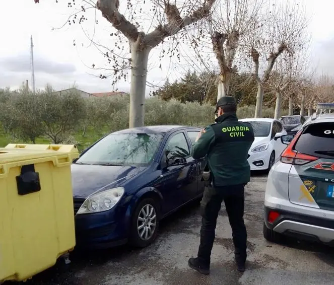 Un agente de la Guardia Civil mira uno de los veh&iacute;culos afectados.