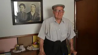 Hilario en la entrada de su casa, junto a un retrato de sus padres
