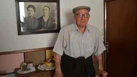 Hilario en la entrada de su casa, junto a un retrato de sus padres