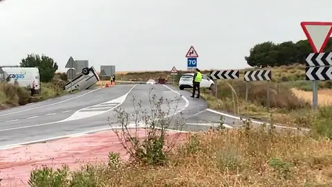 A la izquierda se observa a la furgoneta volcada en un lateral de la calzada
