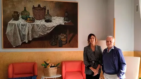 La directora de la residencia Bego&ntilde;a Moreno Valencia y el pintor Jan D&iacute;ez posan ante el cuadro donado