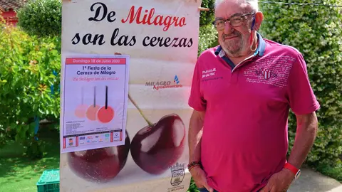 Jesus Mari Barrado Pardo posa al lado de un cartel anunciador de la Fiesta de la Cereza sobre el que está también el que lució  la I Fiesta de la misma, all&aacute; por el año 2000