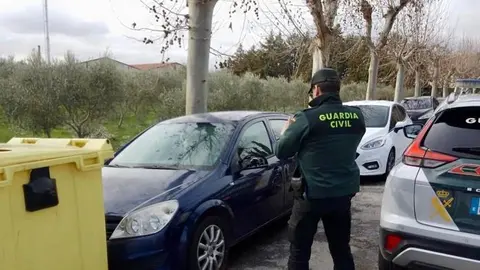 Un agente de la Guardia Civil mira uno de los veh&iacute;culos afectados.