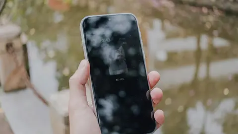 Una mano que sostiene un tel&eacute;fono m&oacute;vil inteligente con reflejos