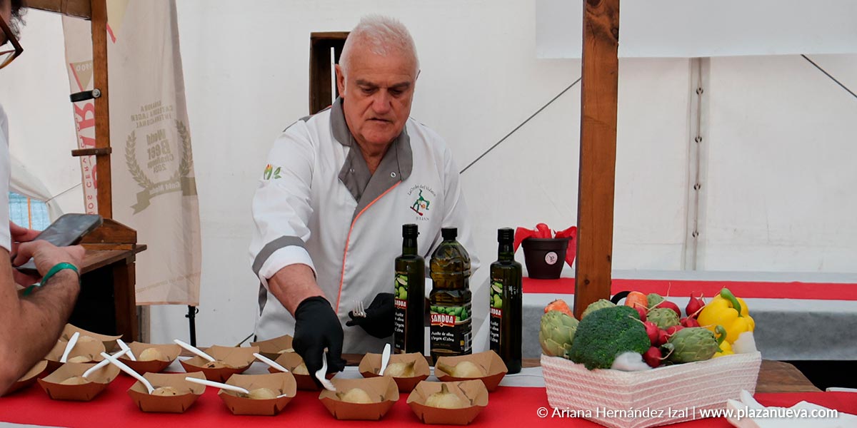 Un miembro de la Orden del Volatín reparte pinchos de cebolla durante la degustación popular en la carpa